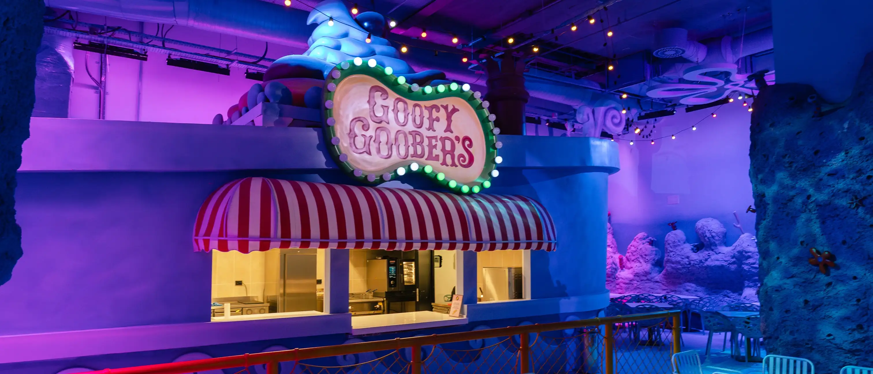 Renkli ışıklarla aydınlatılmış Goofy Goober's restoran tezgahı ve oturma alanı.